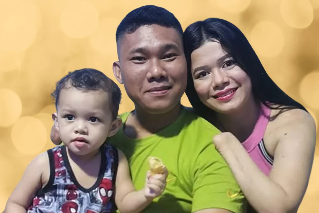 Chef Maricel Apatan posing with her husband in a green shirt and young child in a patterned tank top against a soft gold background.