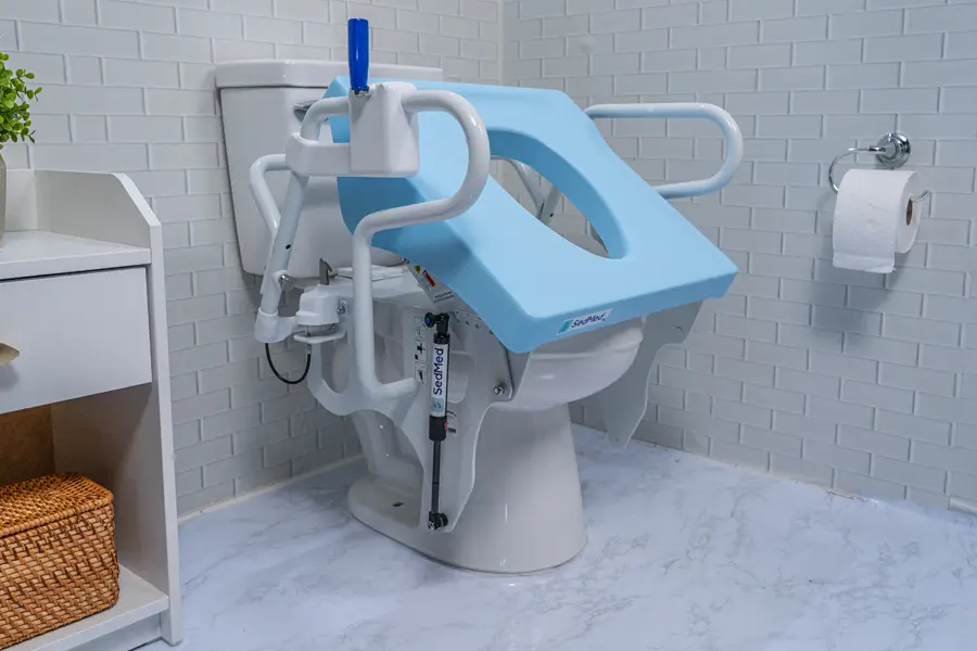A toilet seat fitted with a blue raised accessible seat insert and white adjustable grab bars mounted on either side, installed in a bathroom setting.