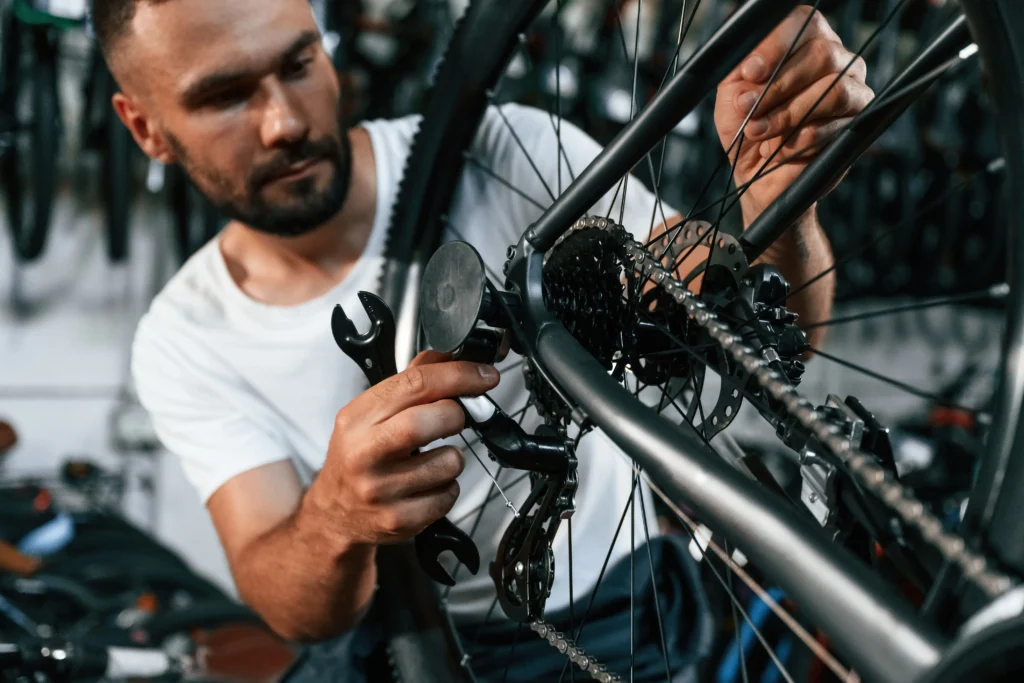 A mechanic using a wrench to adjust the rear derailleur and wheel assembly of a bicycle.